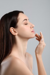 Beautiful young woman with healthy skin on light grey background