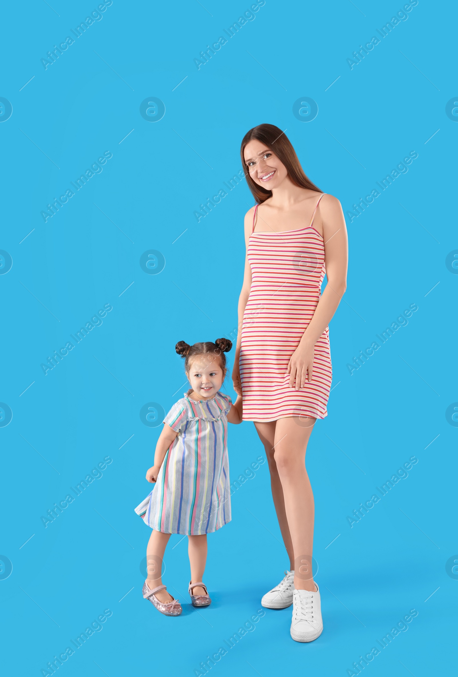 Photo of Young mother and little daughter on blue background