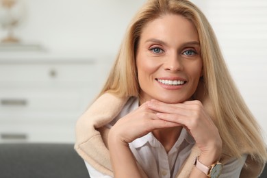 Photo of Portrait of smiling middle aged woman with blonde hair indoors. Space for text