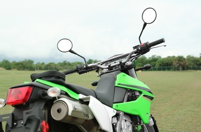 Stylish green cross motorcycle on grass outdoors