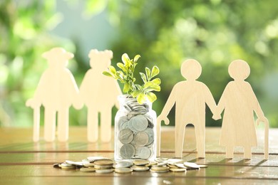 Pension savings. Figures of senior couples, coins and green twigs on wooden table outdoors