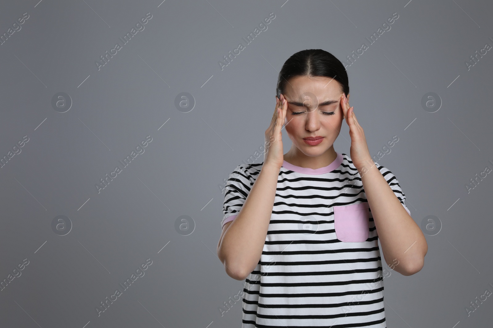 Photo of Young woman suffering from headache on grey background, space for text. Cold symptoms