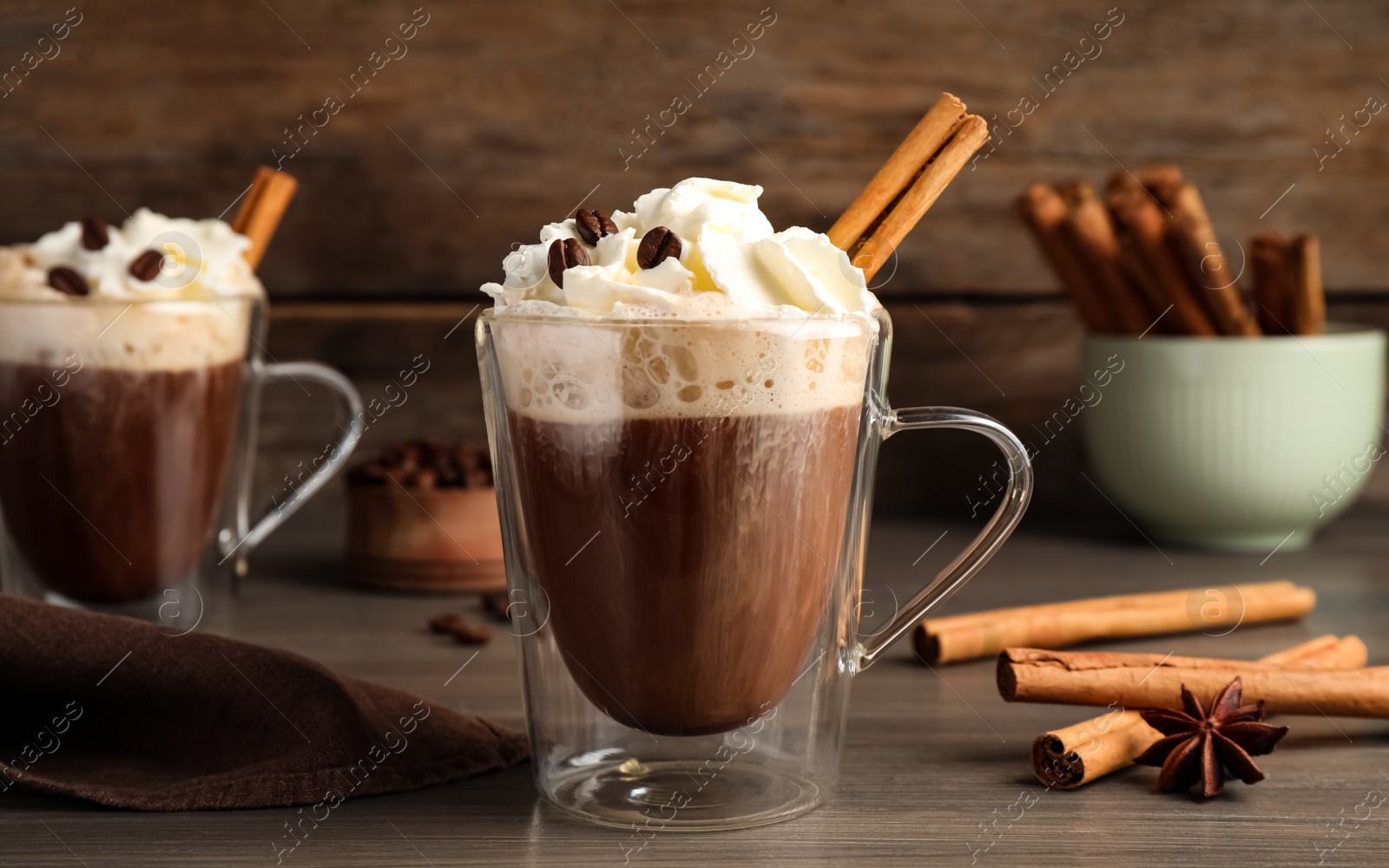 Photo of Delicious coffee with whipped cream and cinnamon on wooden table