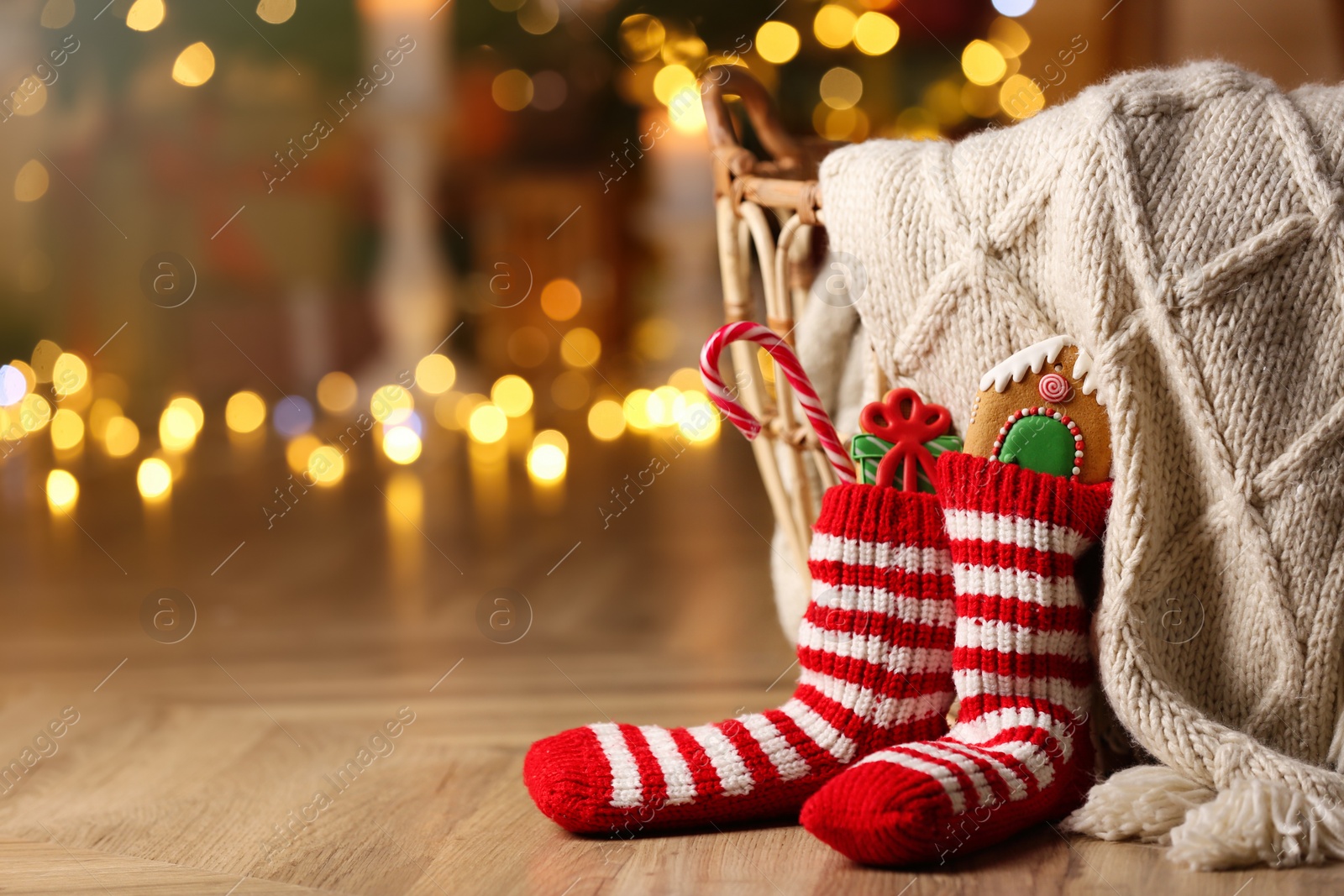 Photo of Socks filled with sweets on floor in room, space for text. Saint Nicholas Day