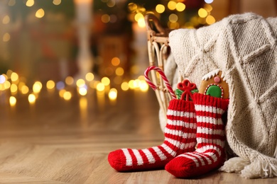 Photo of Socks filled with sweets on floor in room, space for text. Saint Nicholas Day