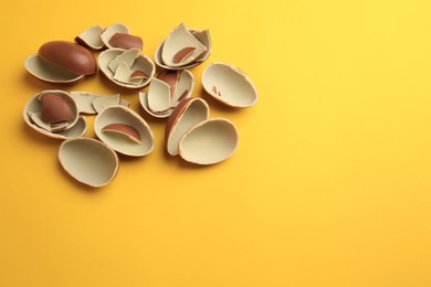 Photo of Sveti Vlas, Bulgaria - July 3, 2023: Broken halves of Kinder Surprise Eggs on yellow background, above view. Space for text