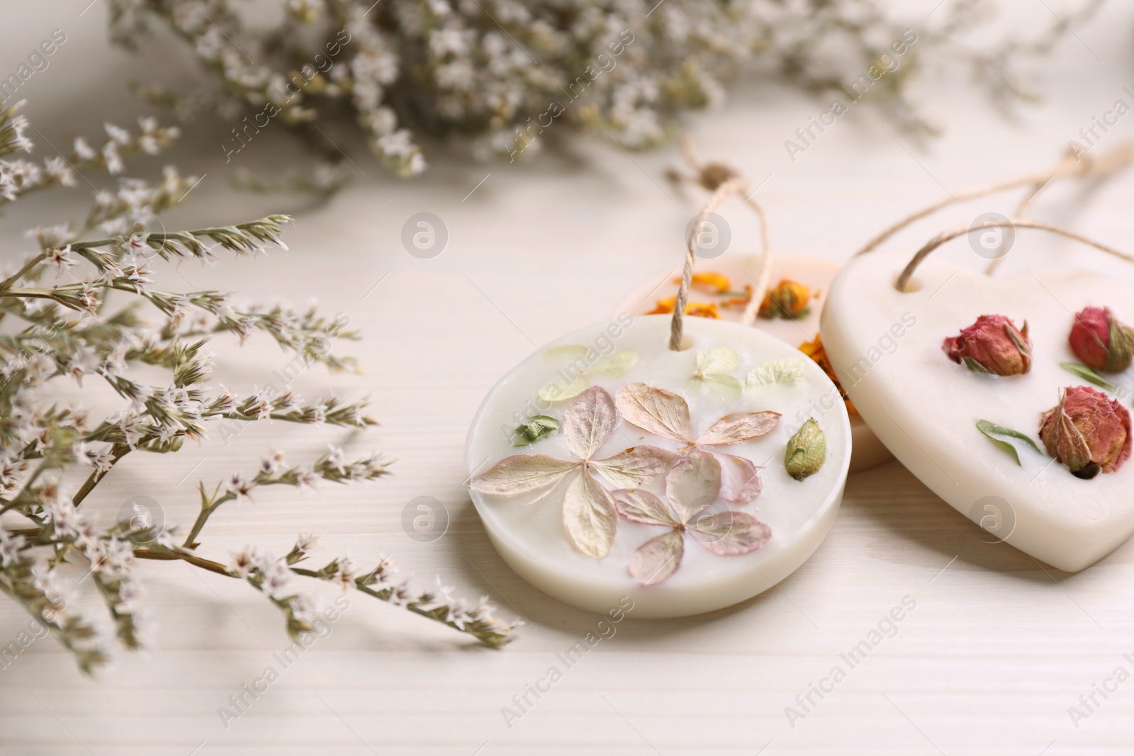 Photo of Scented sachets and flowers on white wooden table