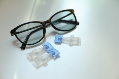 Photo of Single dose eye drops and glasses on white table