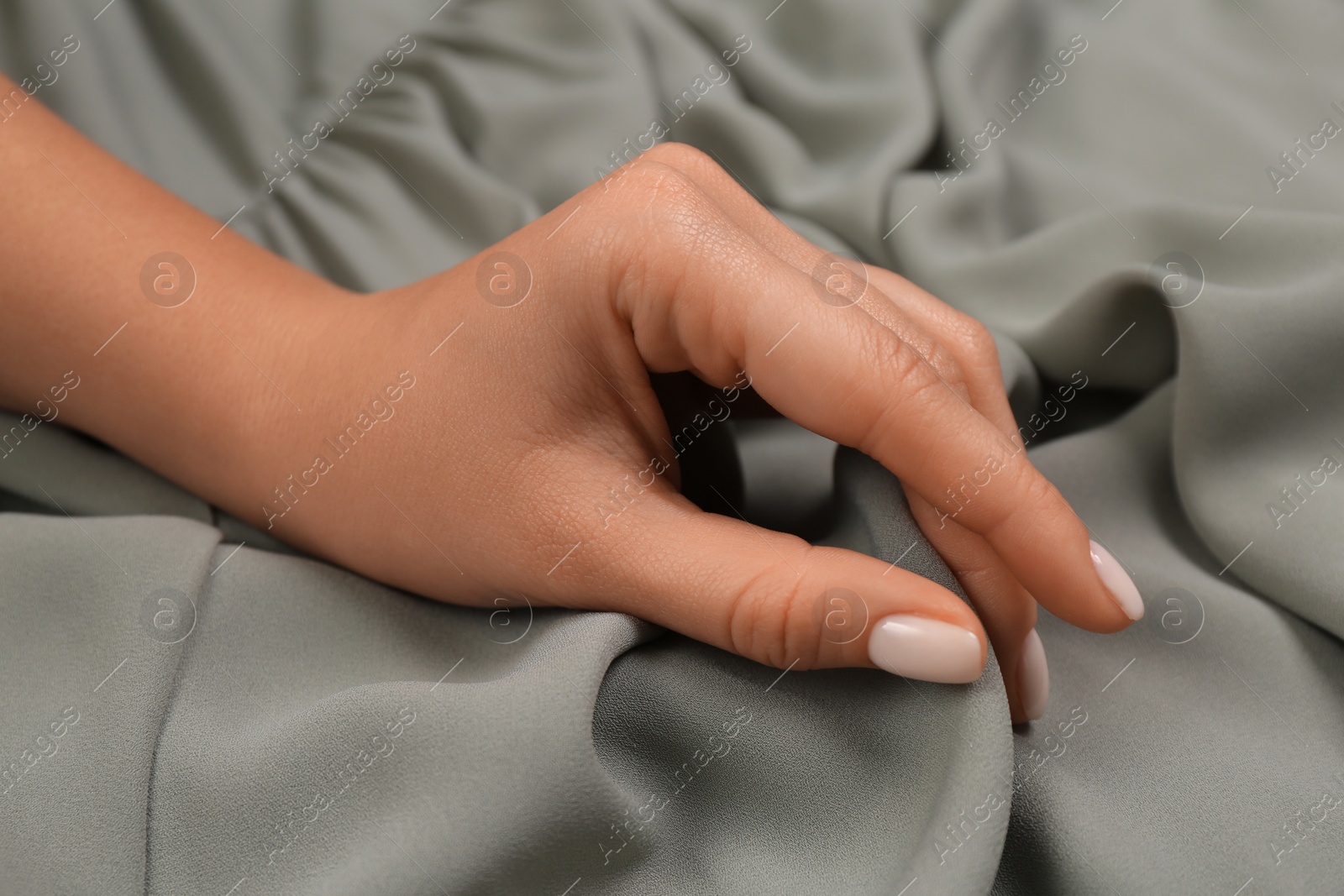 Photo of Woman touching smooth grey fabric, closeup view