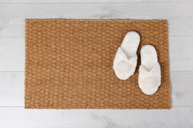 Door mat and slippers on floor, top view. Space for text