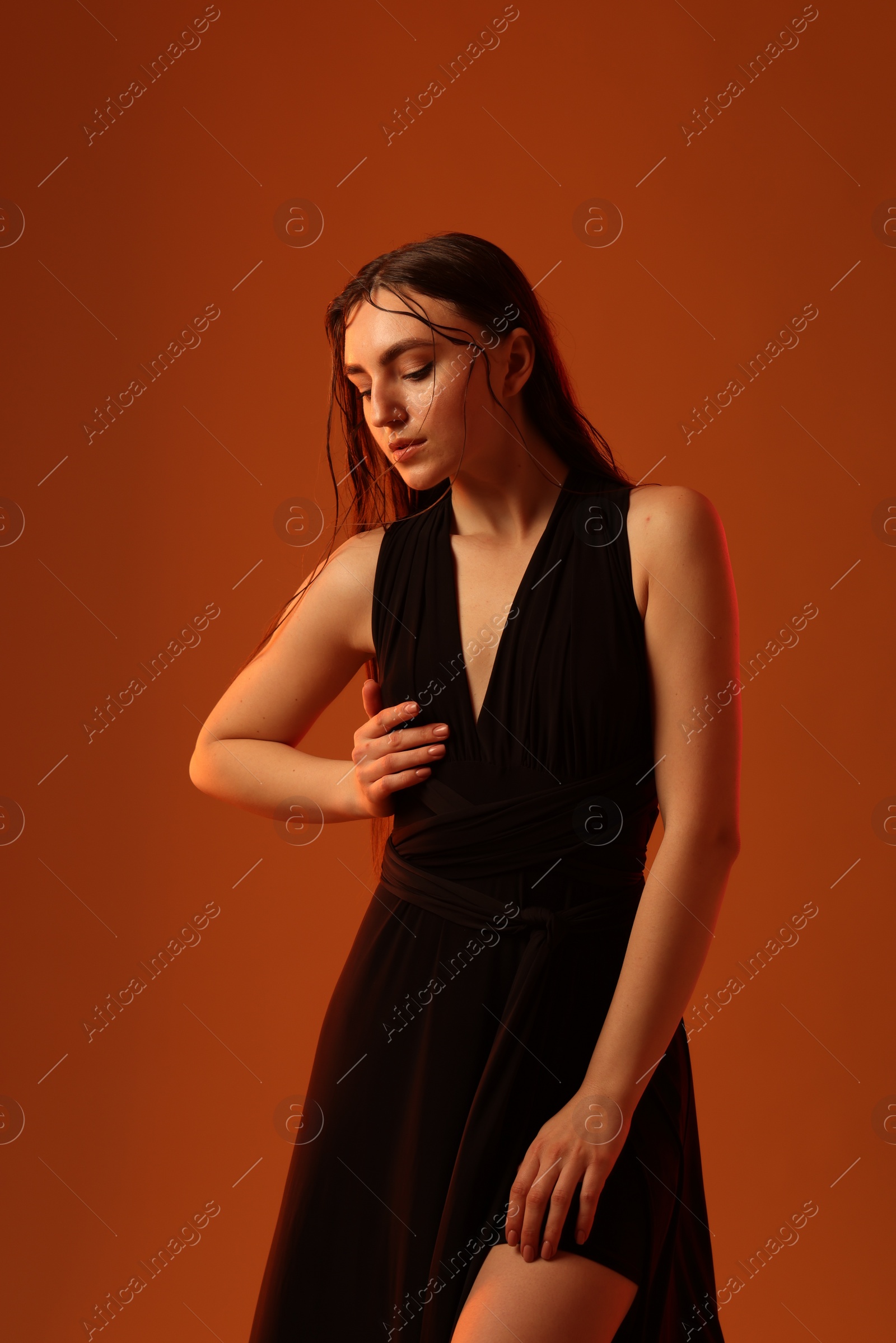 Photo of Beautiful woman in black dress posing on brown background