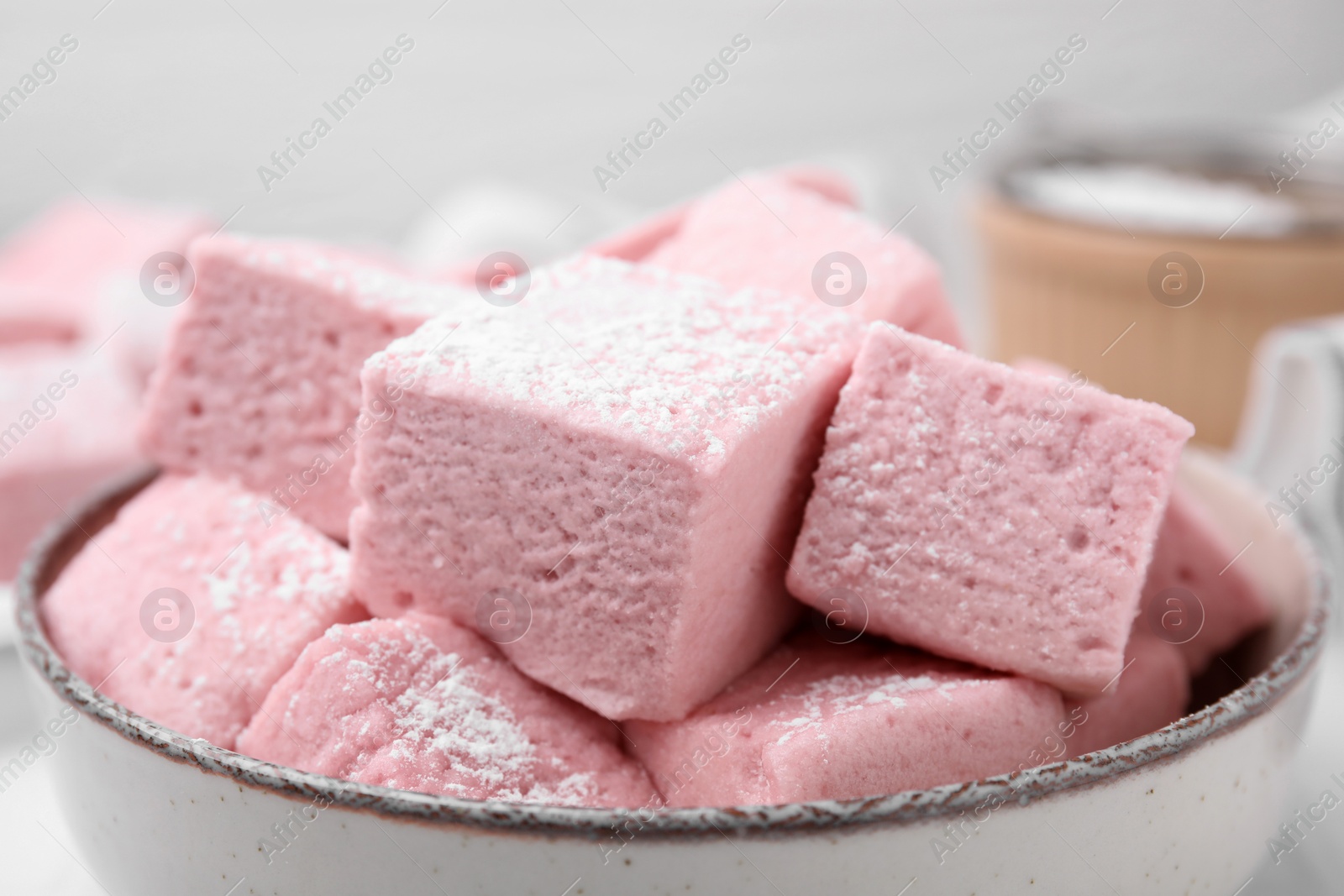 Photo of Bowl of delicious sweet marshmallows with powdered sugar on table, closeup