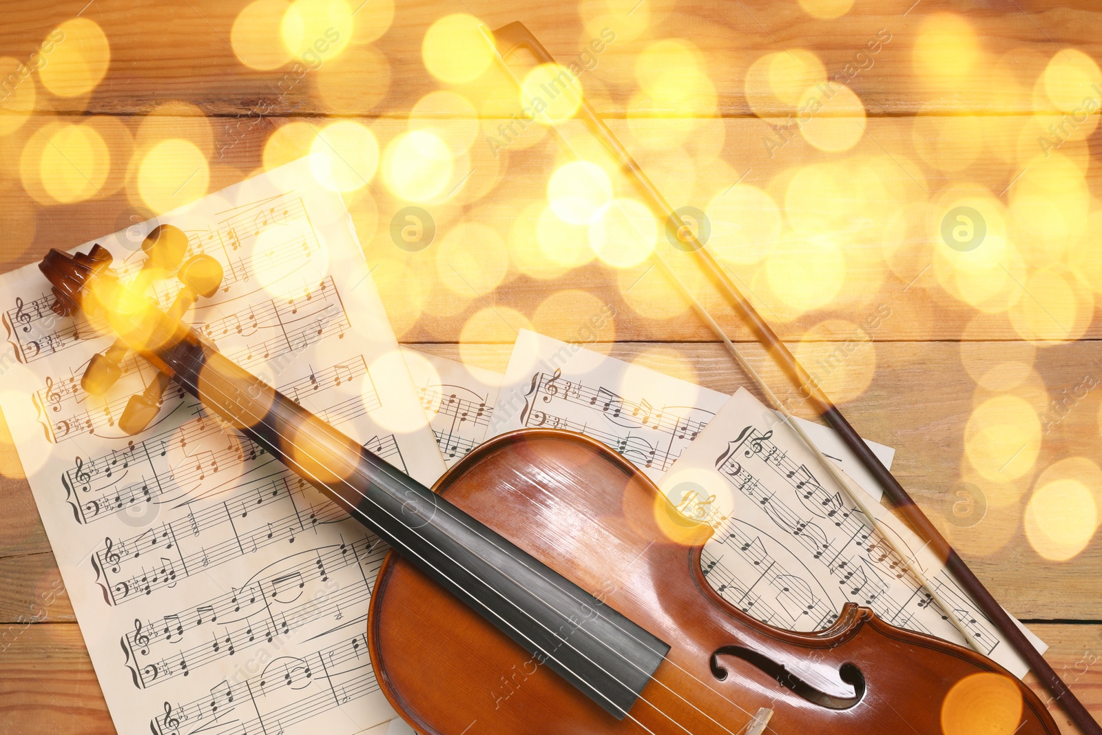 Image of Christmas and New Year music. Violin and music sheets on wooden background, bokeh effect