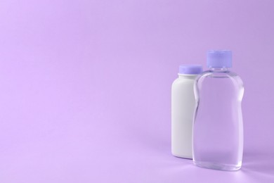 Photo of Bottles with baby oil and powder on violet background. Space for text