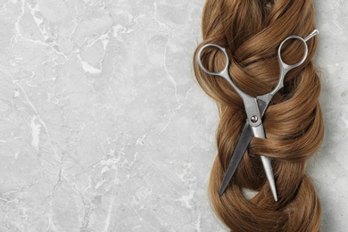 Photo of Flat lay composition with brown hair, scissors and space for text on grey background. Hairdresser service