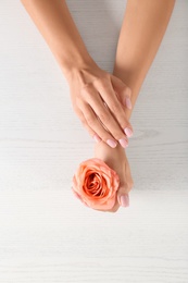Photo of Closeup view of woman with rose at white wooden table. Spa treatment