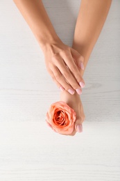 Closeup view of woman with rose at white wooden table. Spa treatment