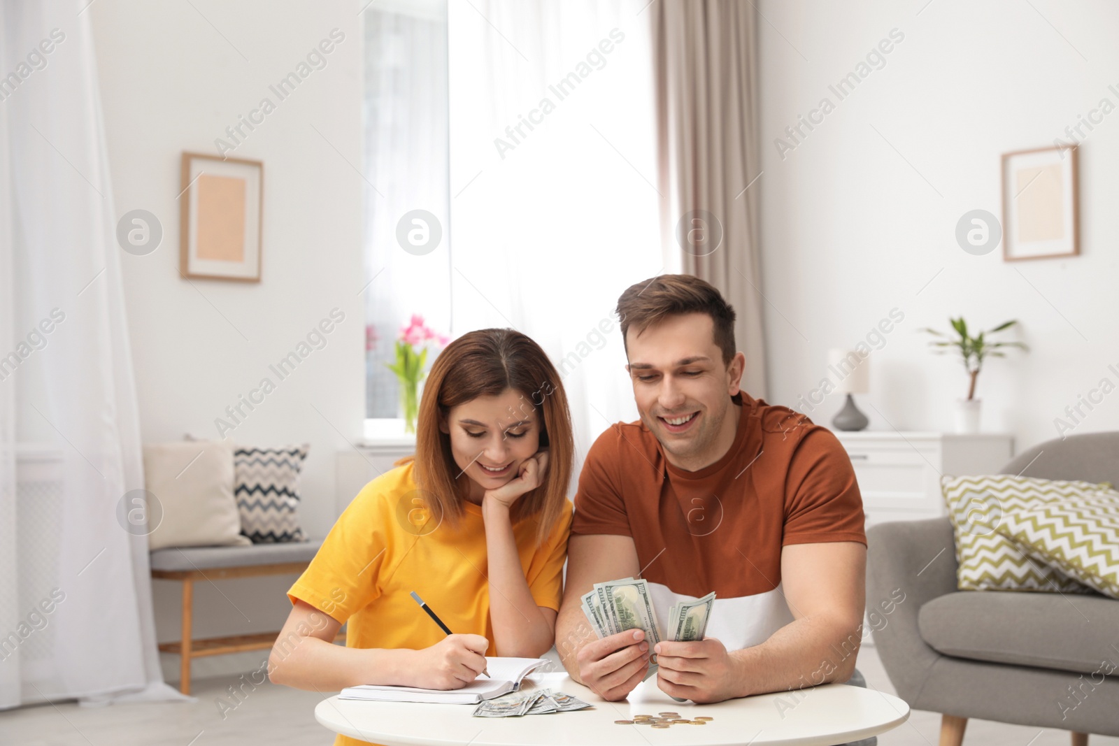 Photo of Couple counting money at table in living room