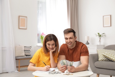 Photo of Couple counting money at table in living room