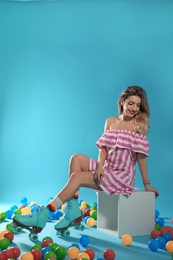 Young woman with retro roller skates on color background