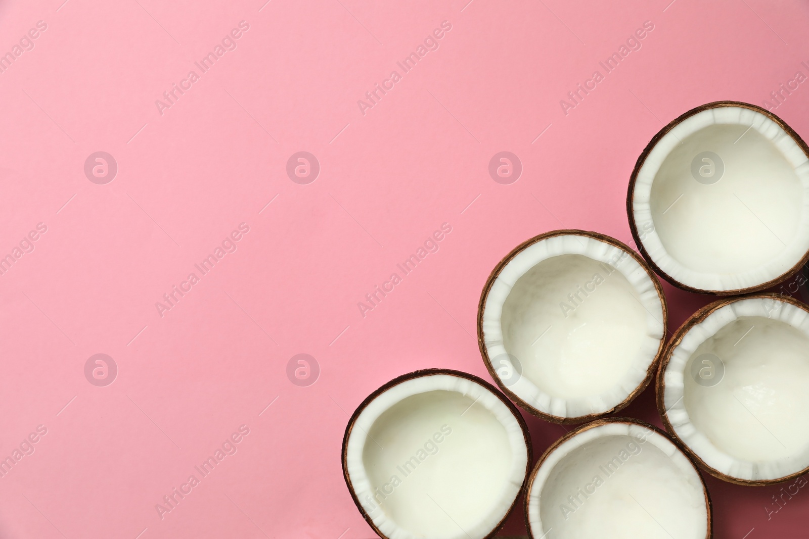 Photo of Fresh coconut halves on pink background, flat lay. Space for text