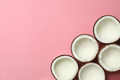 Fresh coconut halves on pink background, flat lay. Space for text