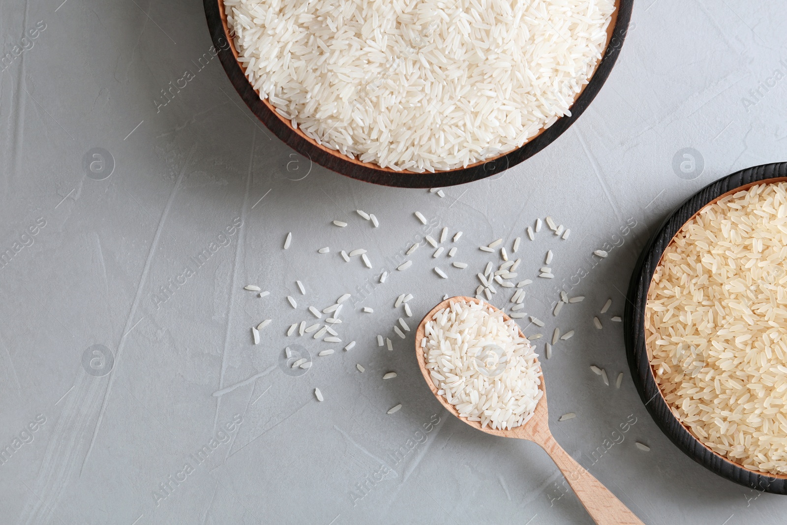 Photo of Flat lay composition with long grain and parboiled rice on grey background. Space for text
