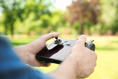 Man holding new modern drone controller outdoors, closeup of hands