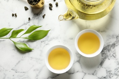 Photo of Flat lay composition with cups of Tie Guan Yin oolong tea on marble background