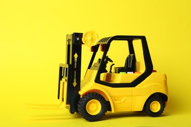 Toy forklift on yellow background. Logistics and wholesale concept
