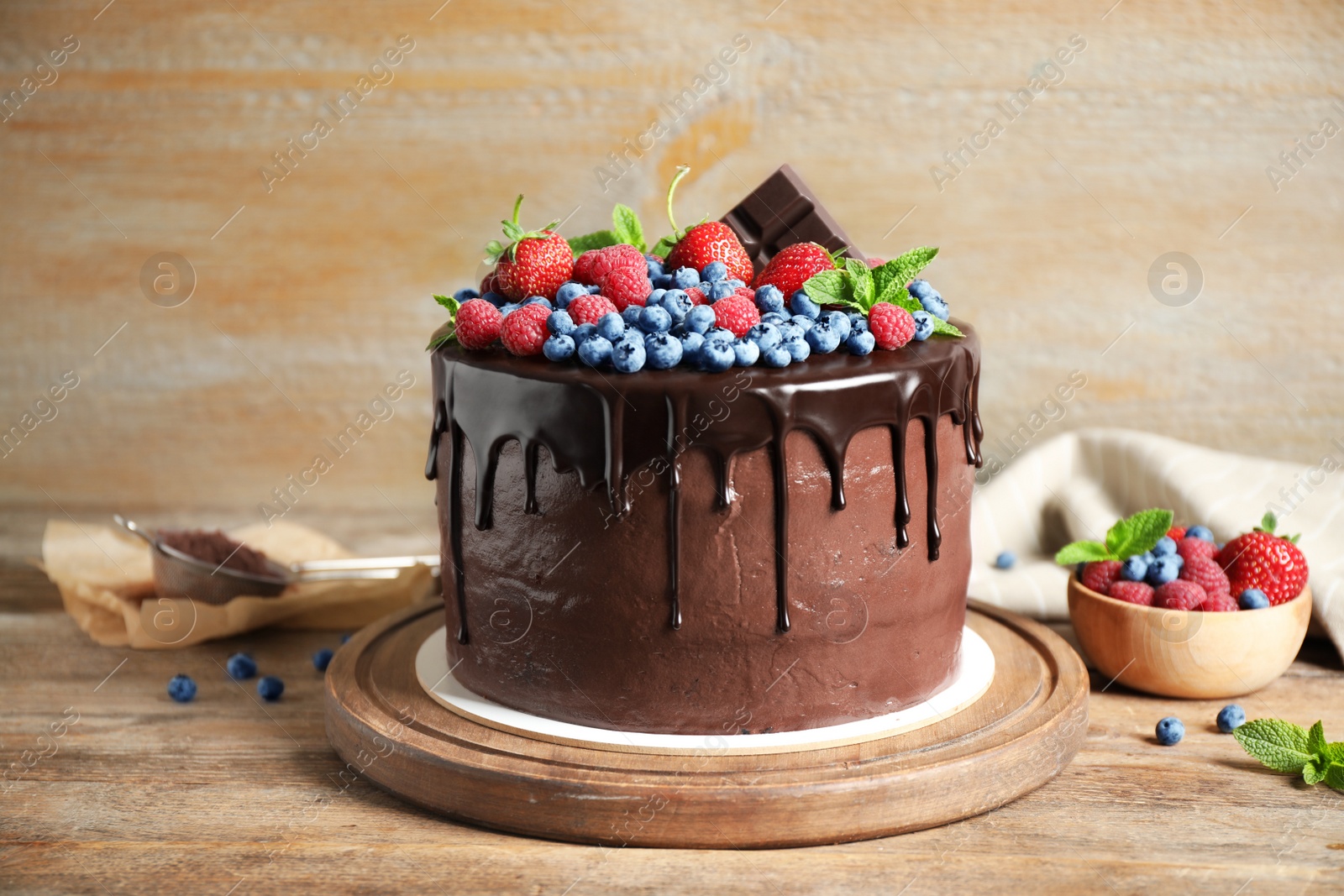 Photo of Freshly made delicious chocolate cake decorated with berries on wooden table