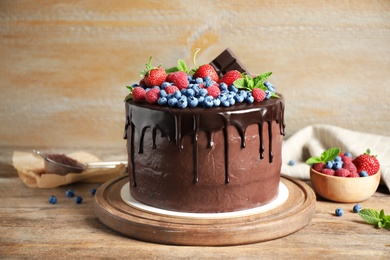 Freshly made delicious chocolate cake decorated with berries on wooden table