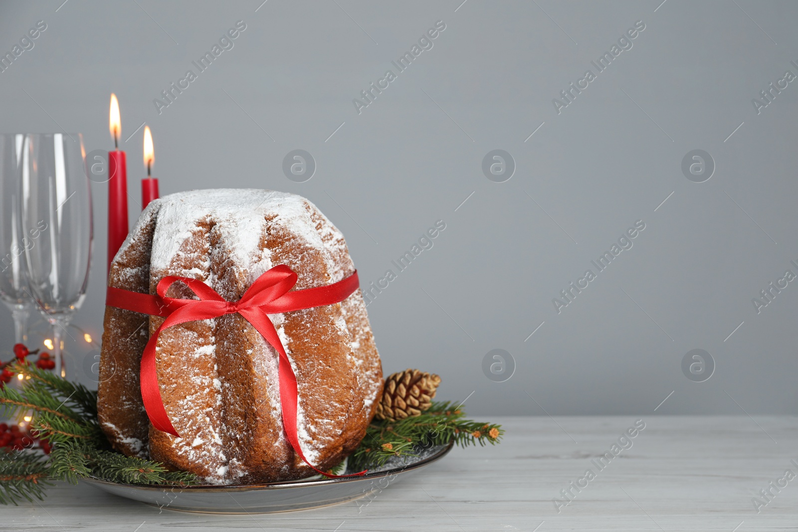 Photo of Delicious Pandoro cake with powdered sugar and Christmas festive decor on white wooden table, space for text. Traditional Italian pastry