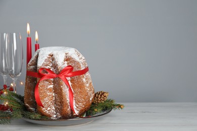 Photo of Delicious Pandoro cake with powdered sugar and Christmas festive decor on white wooden table, space for text. Traditional Italian pastry