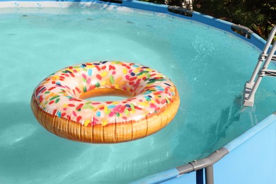 Photo of Inflatable ring floating on water in above ground swimming pool outdoors