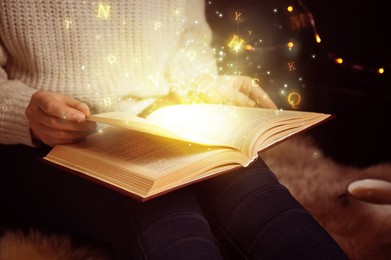 Woman reading shiny magic book with letters flying over it, closeup