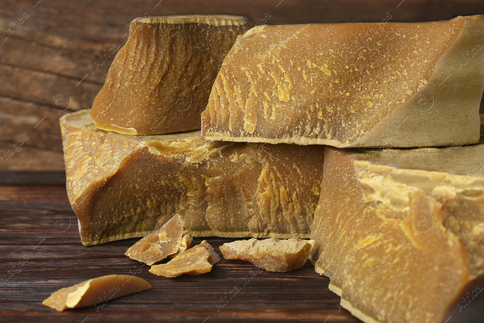 Photo of Natural organic beeswax blocks on wooden table, closeup