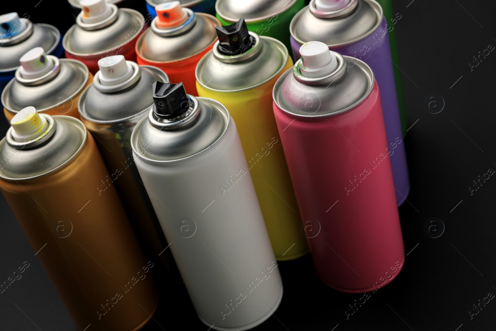 Photo of Cans of different graffiti spray paints on black background