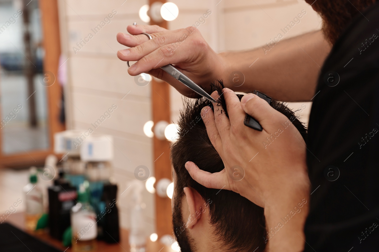 Photo of Professional hairdresser working with client in barbershop, closeup