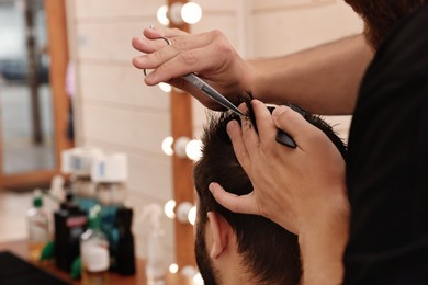 Professional hairdresser working with client in barbershop, closeup