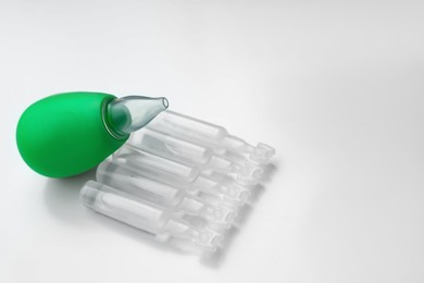 Photo of Single dose ampoules of sterile isotonic sea water solution and nasal aspirator on white background. Space for text