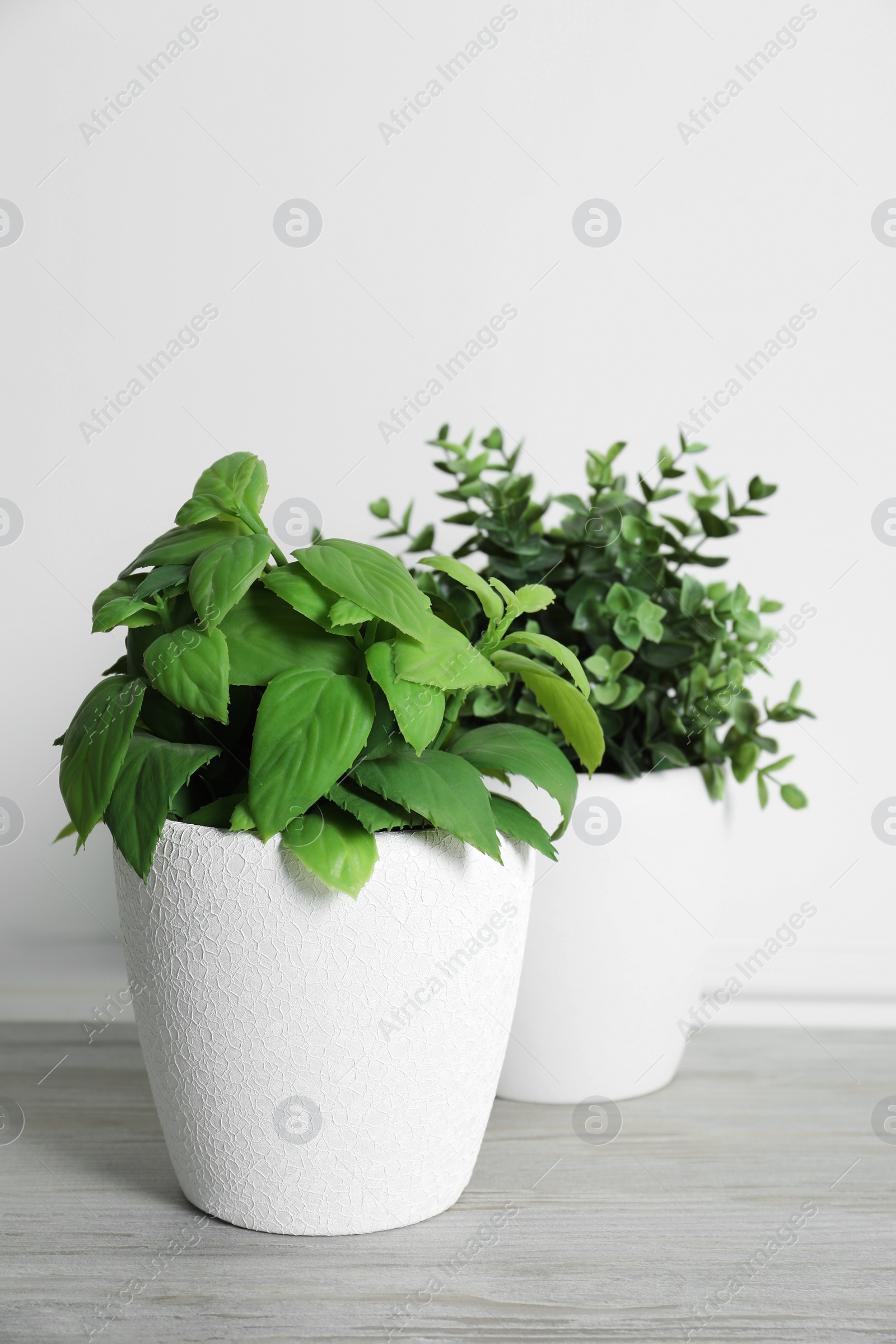 Photo of Different artificial potted herbs on white wooden table