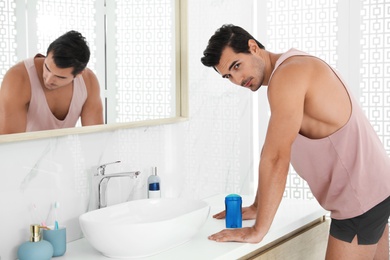 Photo of Handsome young man with deodorant in bathroom