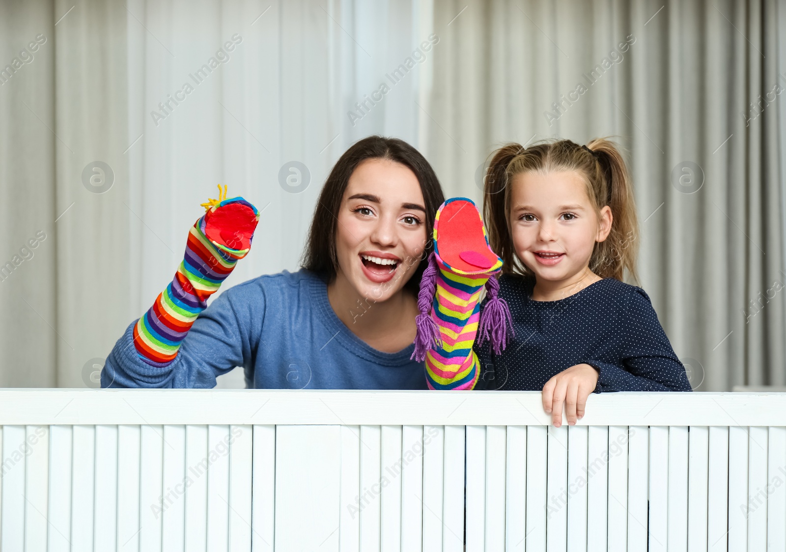 Photo of Mother and daughter performing puppet show at home