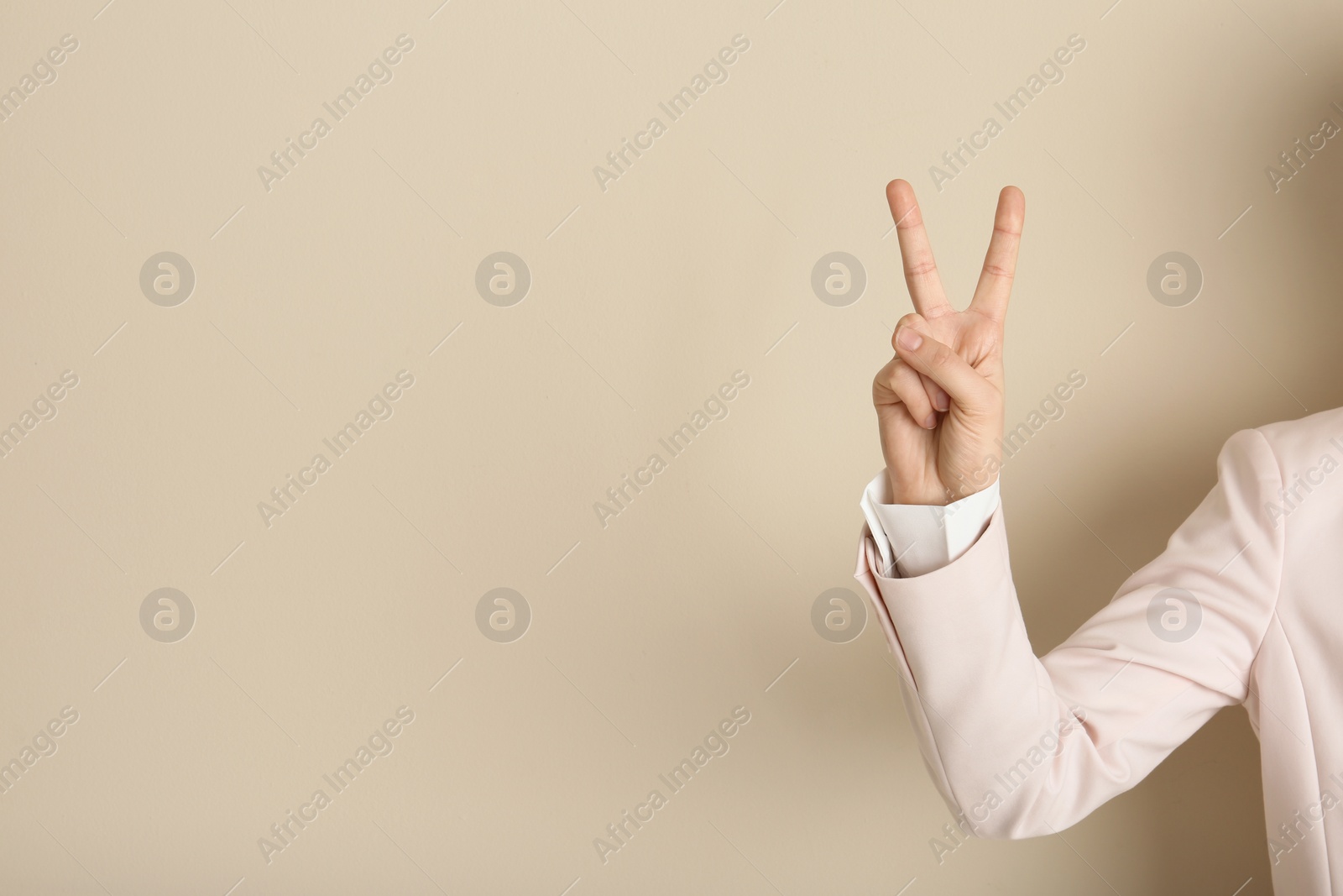 Photo of Young woman showing victory gesture on color background. Space for text