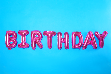 Photo of Word BIRTHDAY made of pink foil balloon letters on light blue background