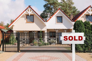 Image of White wooden Sold sign near new house outdoors