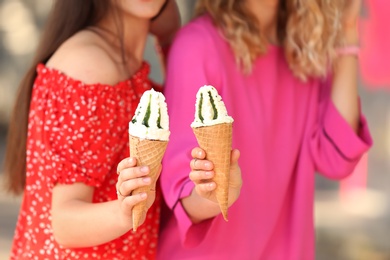 Photo of Young women with delicious ice cream cones outdoors, closeup
