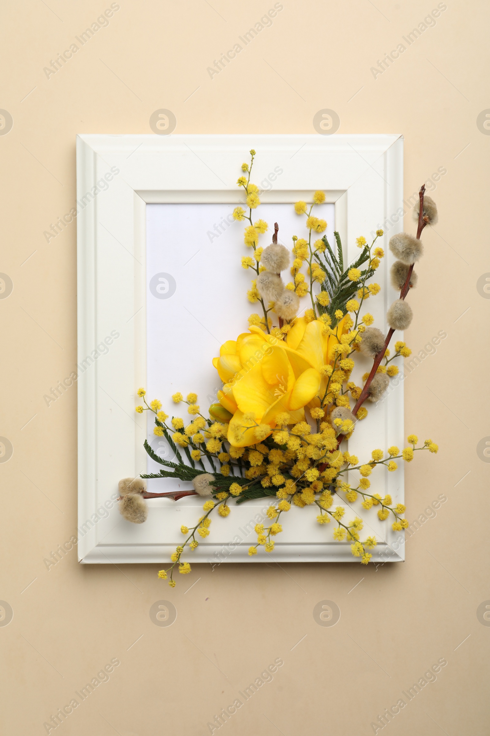 Photo of Beautiful floral composition with mimosa flowers and frame on beige background, top view