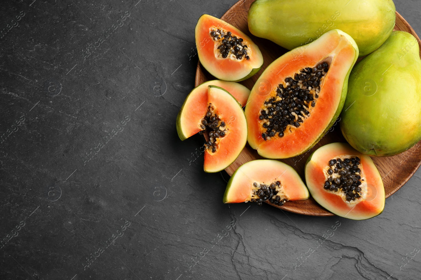 Photo of Fresh ripe papaya fruits on black background, flat lay. Space for text